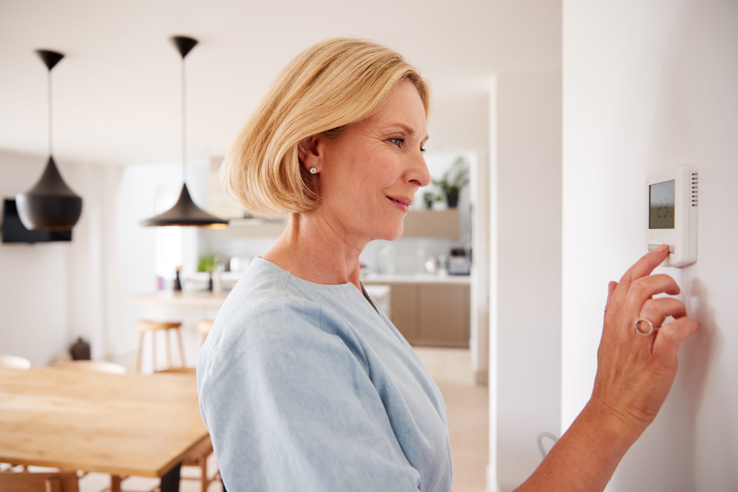 Woman using heating and air thermostat